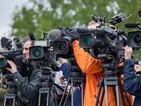 Presseinformationen Journalisten stehen mit ihren Kameras und ihren Stativen nebeneinander. Alle Objektive schauen in eine Richtung.