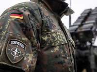 Verlegung - eVA POL Ein Soldat mit einem NATO-Ärmelabzeichen steht vor dem Waffensystem Patriot